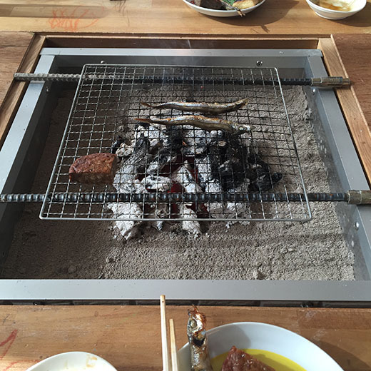 囲炉裏の炭火でシシャモを炙っている画像